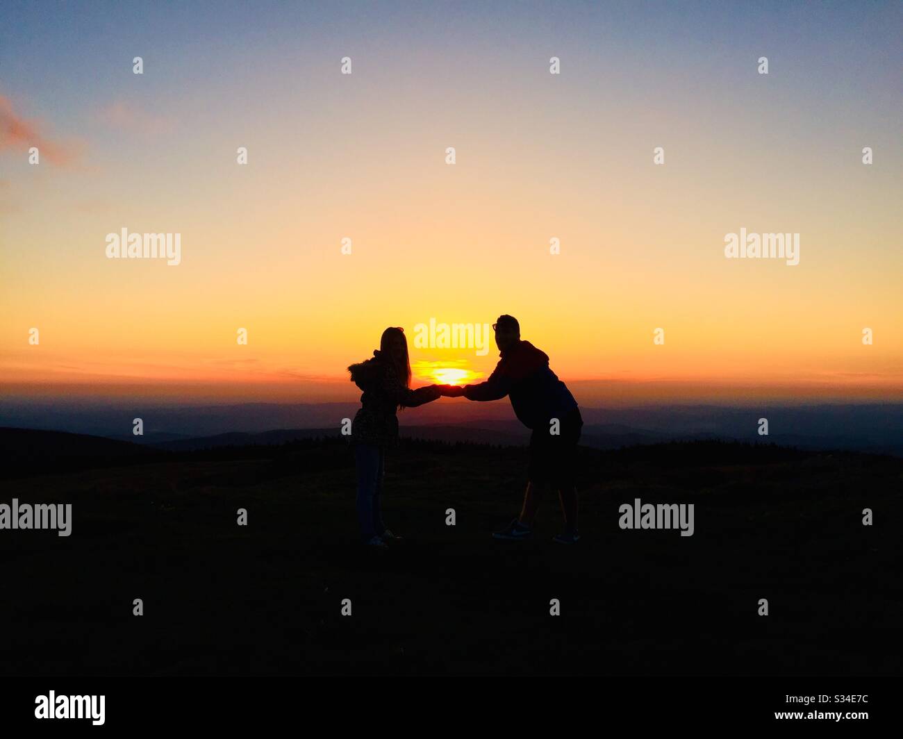 Silhouette of couple holding hands at dusk - Smartphone Captured Stock Image