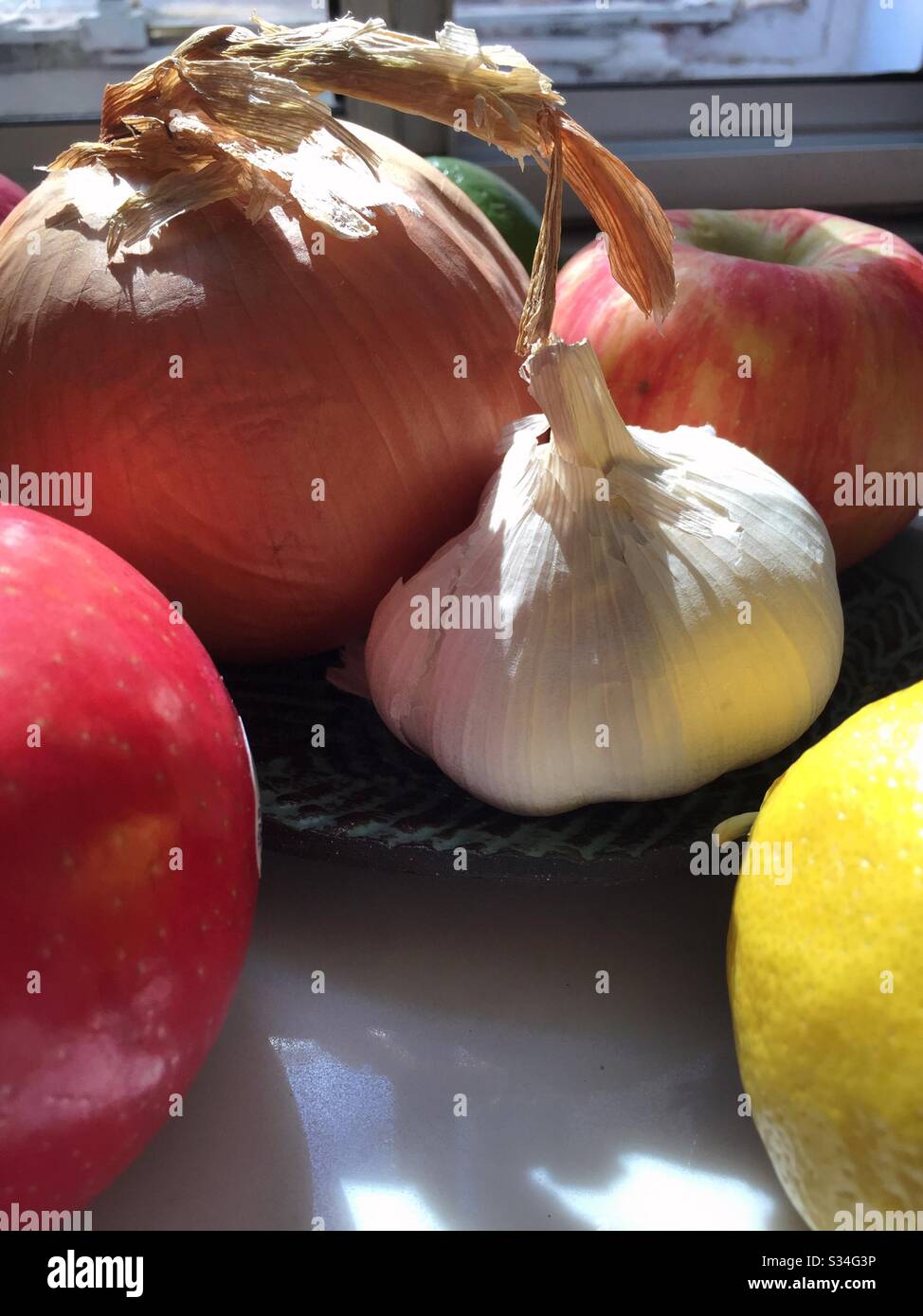 Close up of garlic, onion, apples and lemon on the kitchen window ledge, USA - Smartphone Captured Stock Image