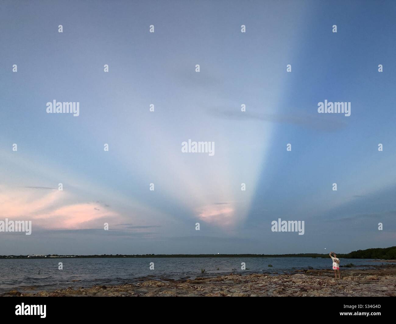 Lonely teenager alone on a beach at sunset. In Darwin, Northern Territory, Australia. - Smartphone Captured Stock Image