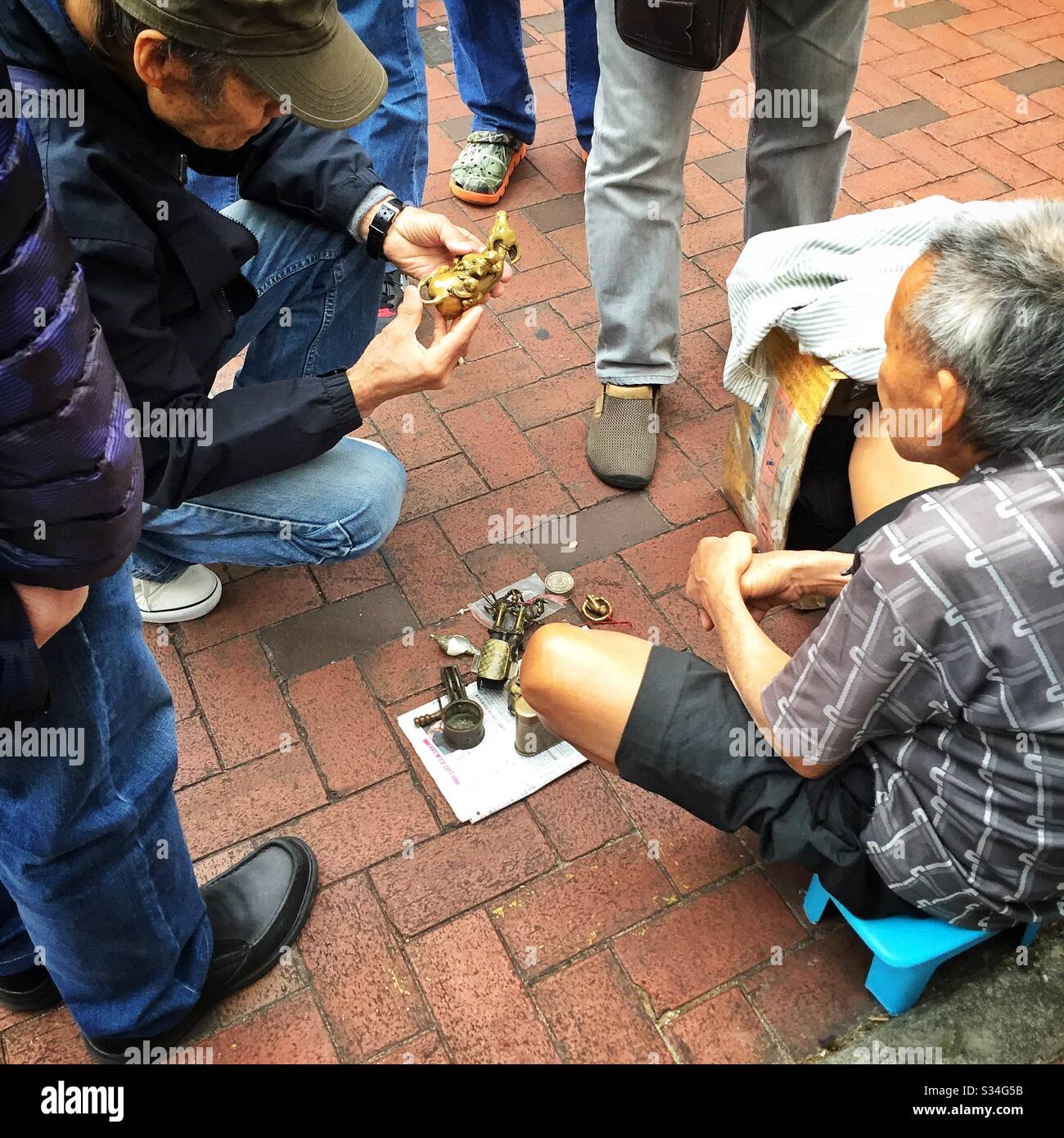 A hawker sells metal antiques, curios and old coins in the street, Sham Shui Po, Kowloon, Hong Kong - Smartphone Captured Stock Image