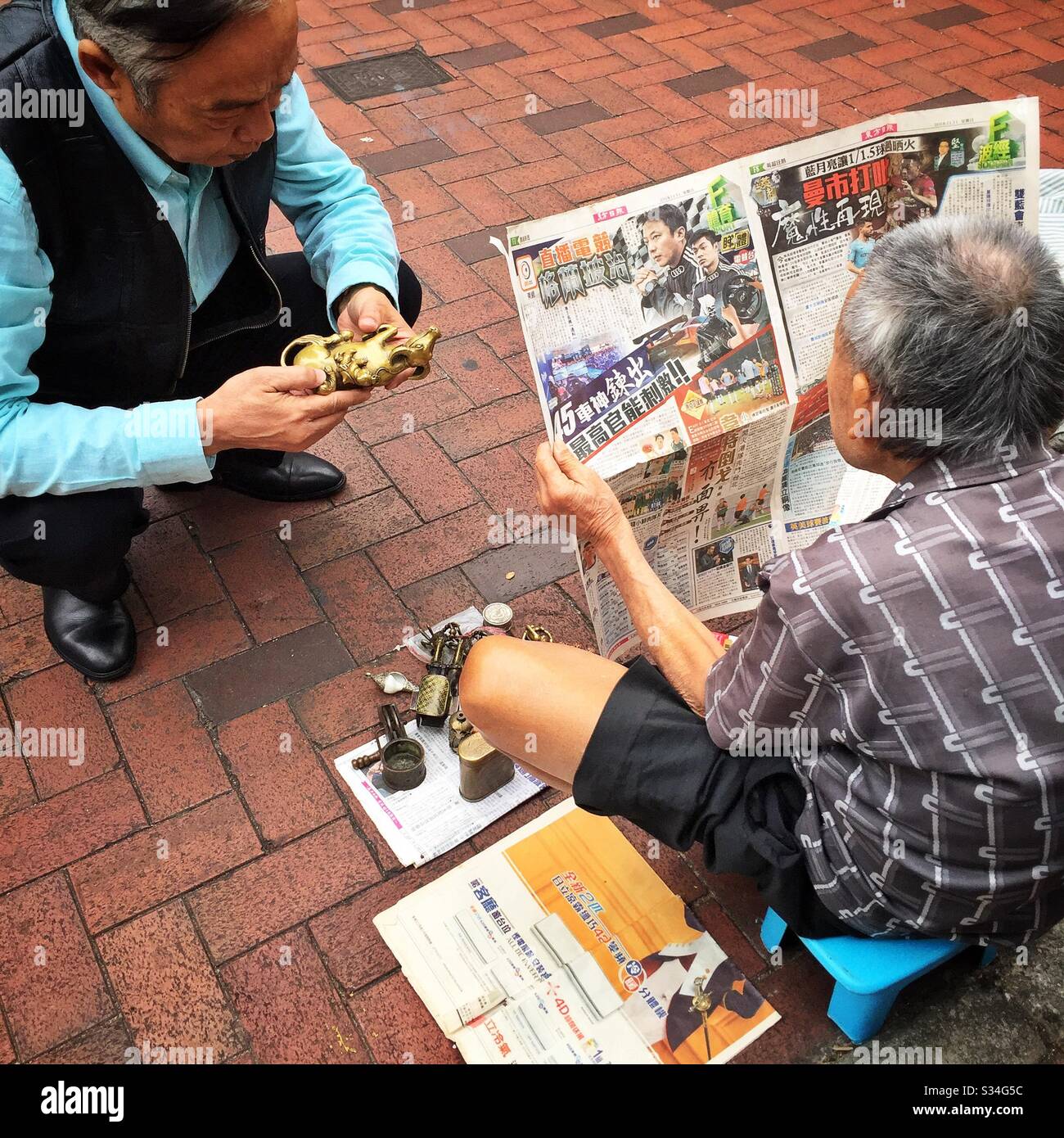 A hawker sells metal antiques, curios and old coins in the street, Sham Shui Po, Kowloon, Hong Kong - Smartphone Captured Stock Image