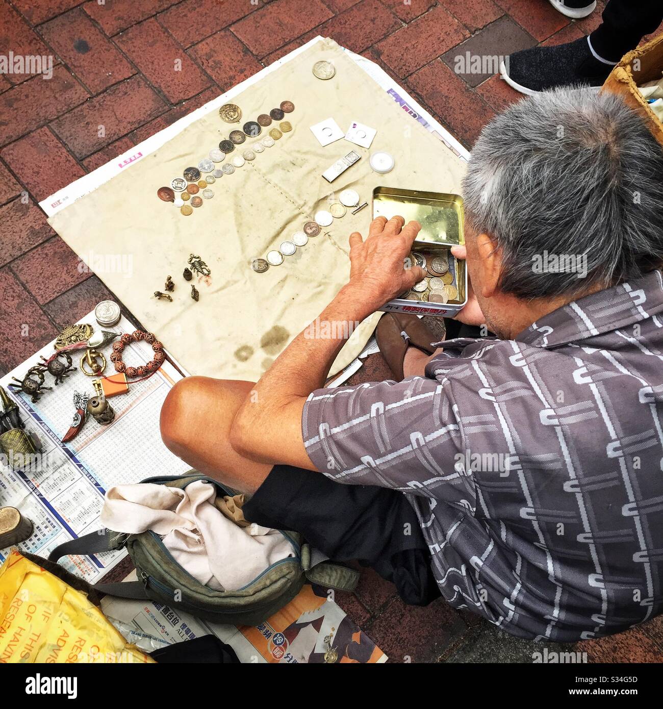 A hawker sells metal antiques, curios and old coins in the street, Sham Shui Po, Kowloon, Hong Kong - Smartphone Captured Stock Image
