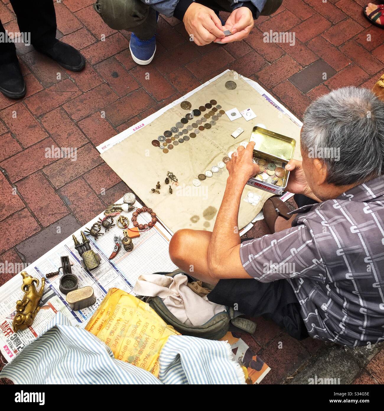A hawker sells metal antiques, curios and old coins in the street, Sham Shui Po, Kowloon, Hong Kong - Smartphone Captured Stock Image