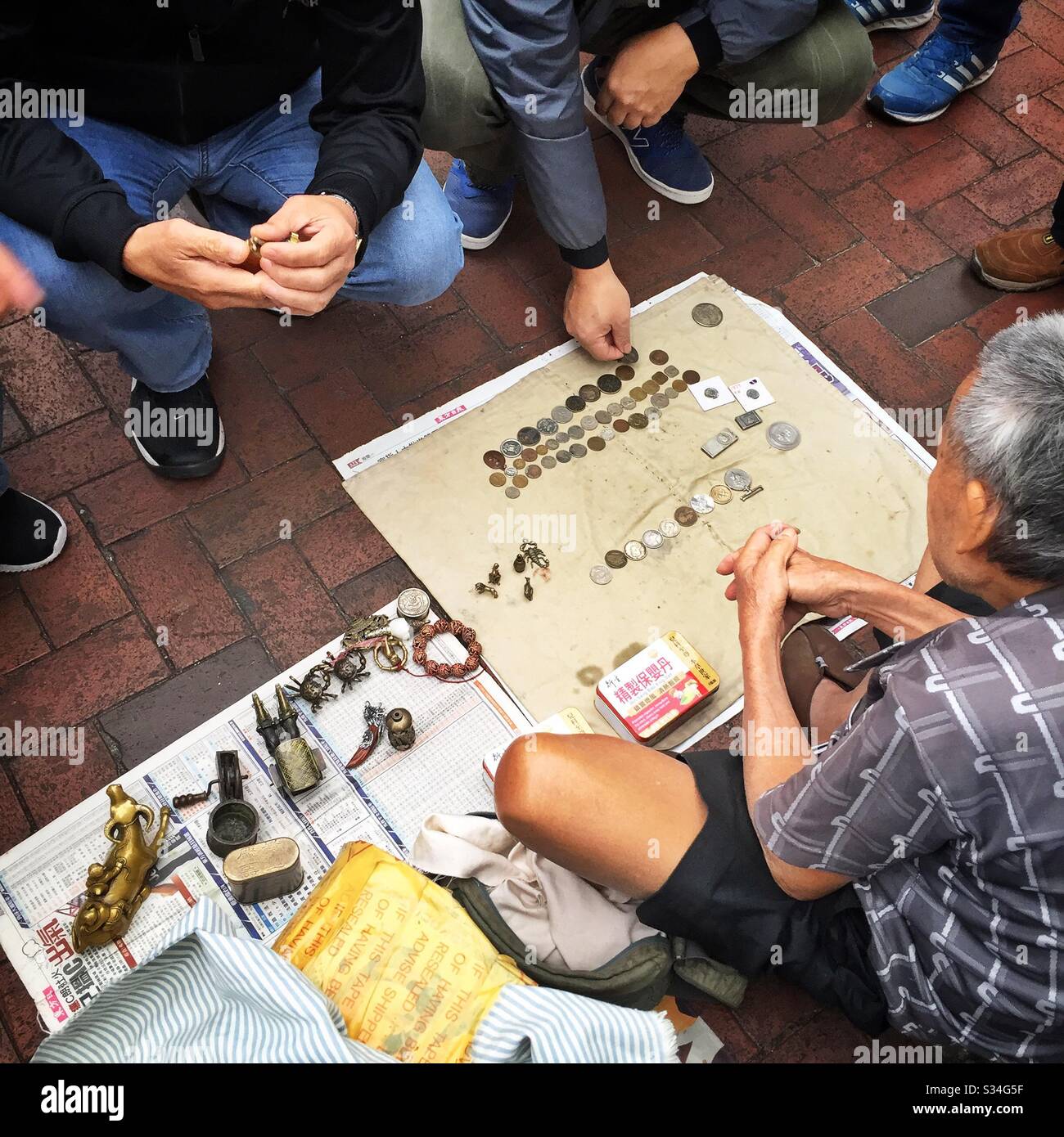 A hawker sells metal antiques, curios and old coins in the street, Sham Shui Po, Kowloon, Hong Kong - Smartphone Captured Stock Image