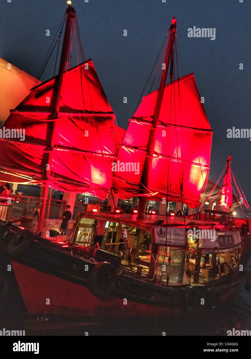 The 'Duk Ling', a restored 1950s Chinese fishing junk, picks up passengers for a sightseeing tour of Victoria Harbour, Hong Kong - Smartphone Captured Stock Image