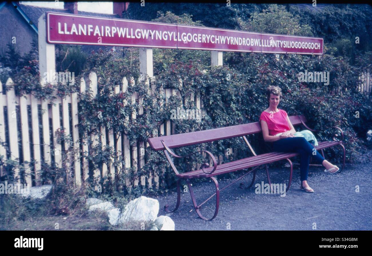 Beautiful woman sitting at train station in wales, longest name in the world Stock Photo