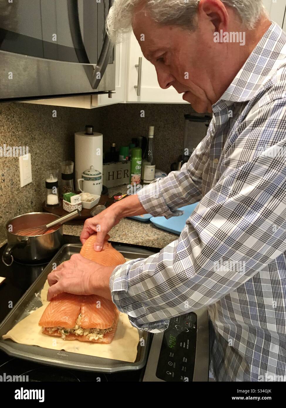 Man at home preparing crab stuffed salmon in pastry dough. - Smartphone Captured Stock Image