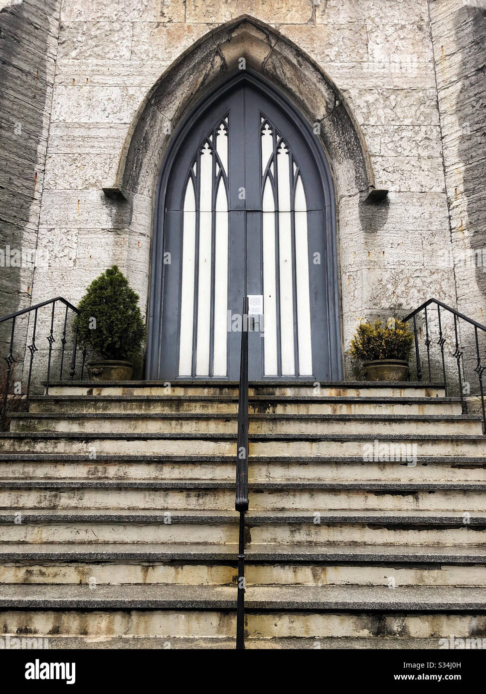 Church doors in a painted, arched, gothic style and the stairs that lead to them - Smartphone Captured Stock Image