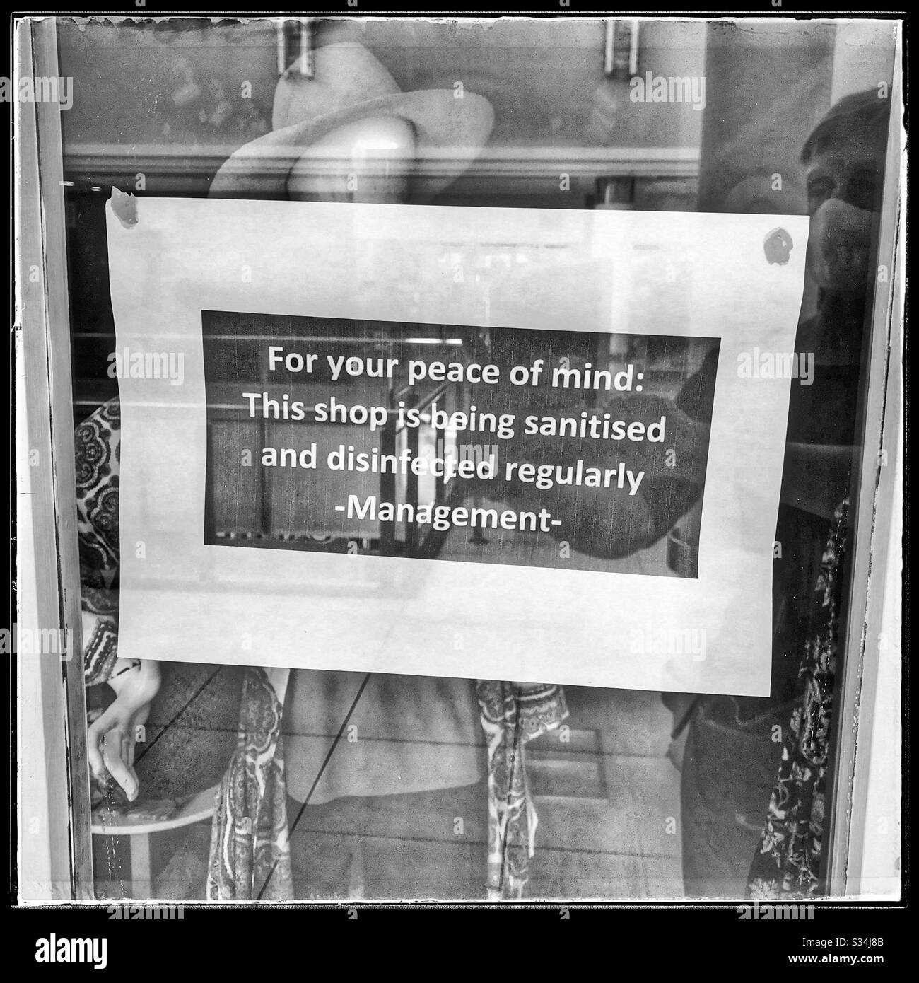 Reflection of person with mask on taking photo of safety notice in closed shop window during coronavirus crisis. - Smartphone Captured Stock Image