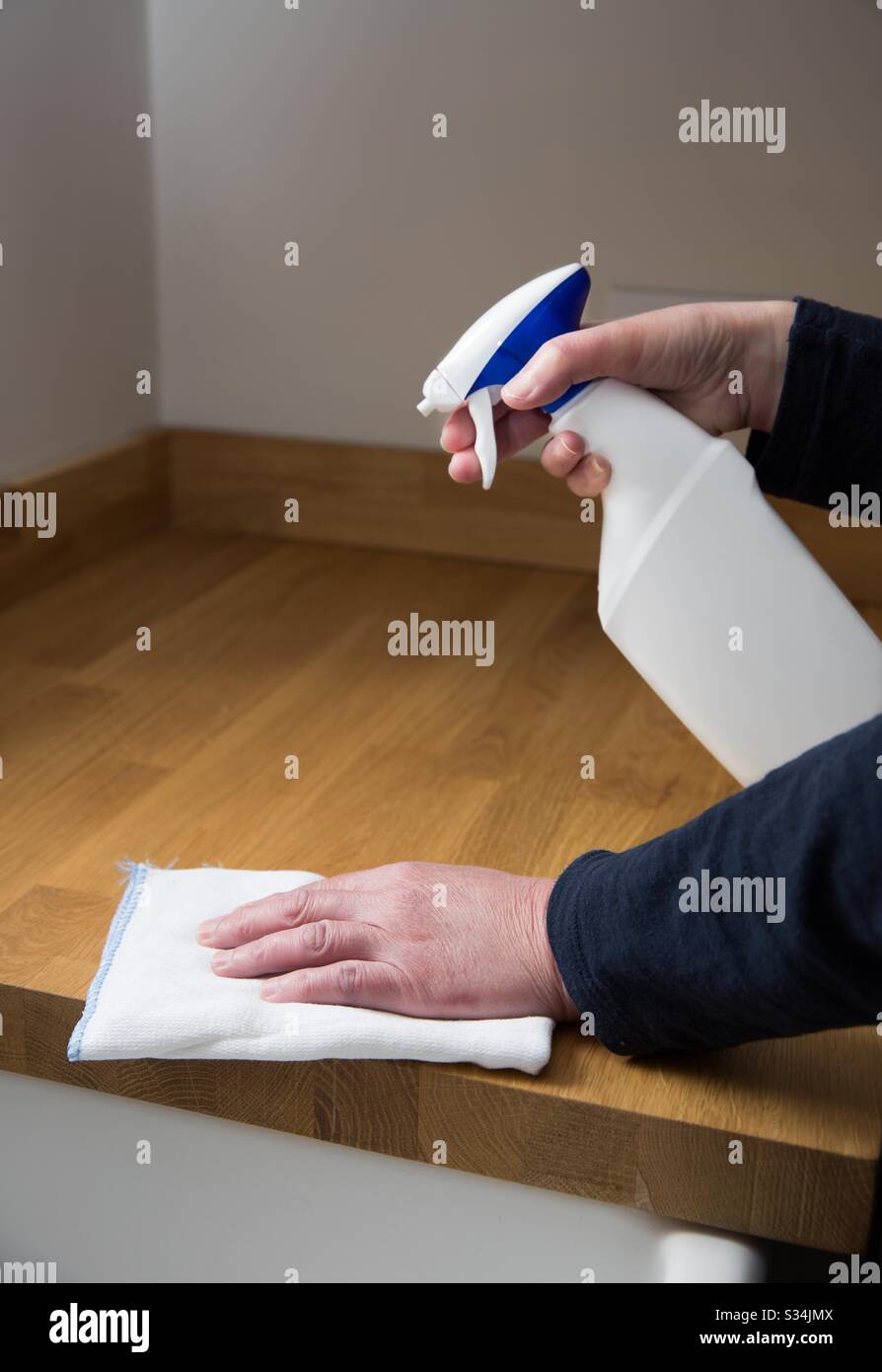 A close-up of a persons hands doing housework by disinfecting and sanitising kitchen worksurfaces during the coronavirus outbreak - Smartphone Captured Stock Image