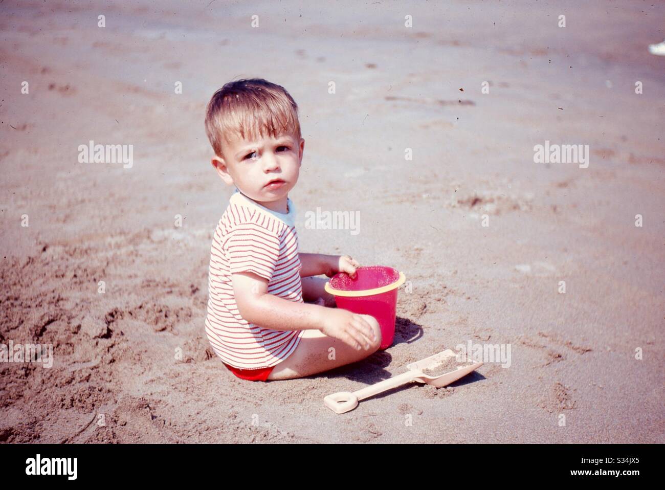 Boy on sand with bucket and spade Stock Photo