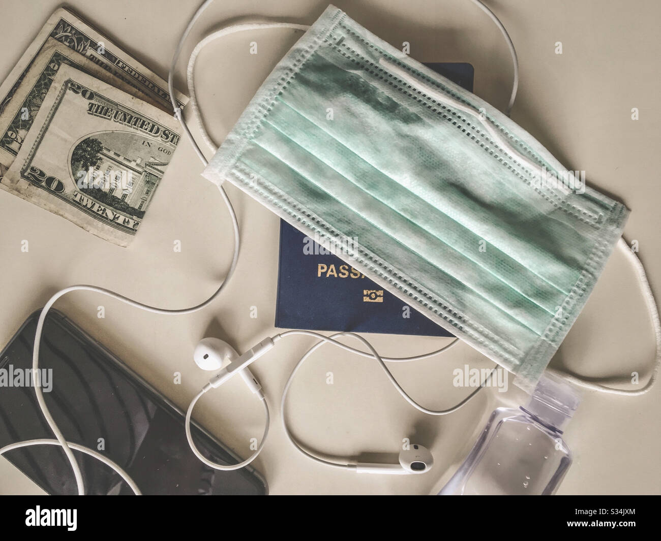 Travel concept: alcohol gel, facial mask, mobile phone, headset, US dollars and passport. In times of pandemic, the tourism sector is affected. Stock Photo