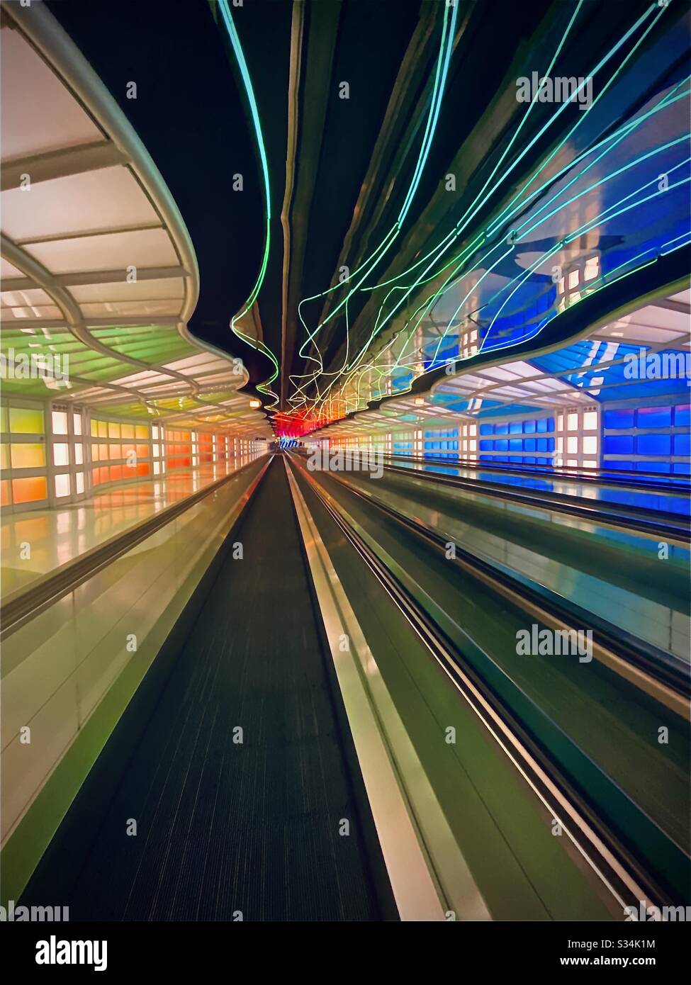 O’Hare International Airport in Chicago, Illinois. Tunnel between Concourses B and C of United Terminal with moving colorful neon lights and moving walkway. Stock Photo