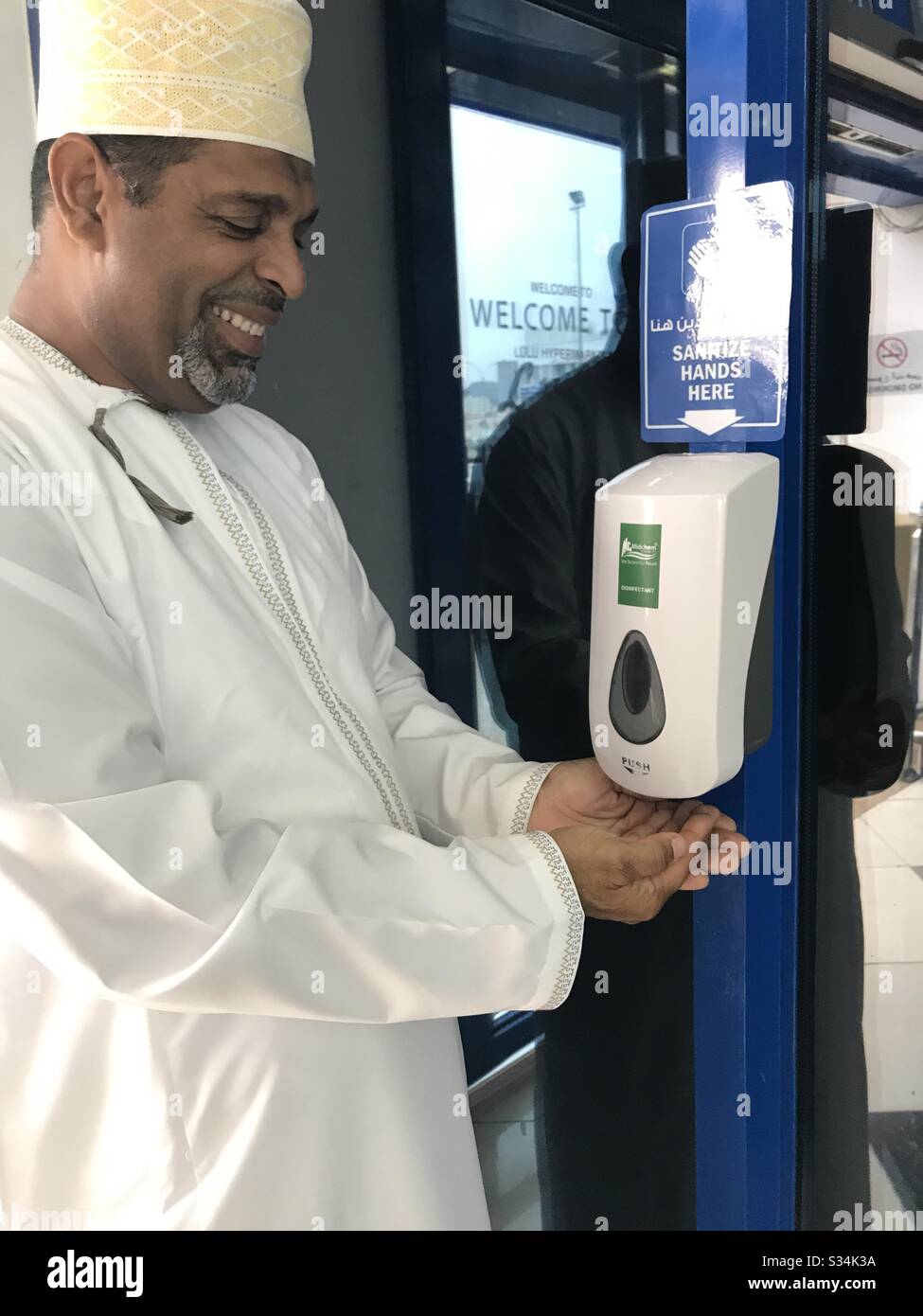 Keep Hands clean: A man using a sanitizing gel to keep his hands clean before entering a supermarket - Smartphone Captured Stock Image