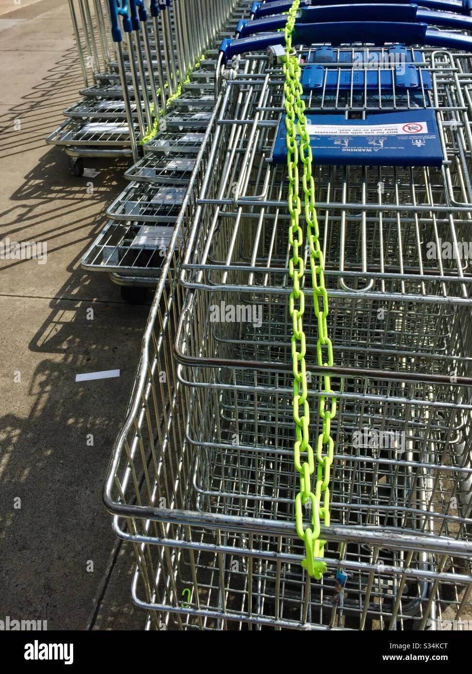 Chain locked parked shopping carts at IKEA during store closure shelter-in-place order due to COVID19 or coronavirus. Emeryville, California. - Smartphone Captured Stock Image