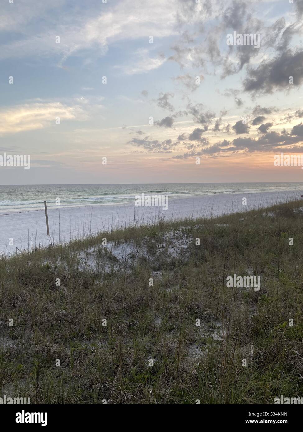 Soft sunset skies over the Gulf of Mexico water with green sand dunes - Smartphone Captured Stock Image