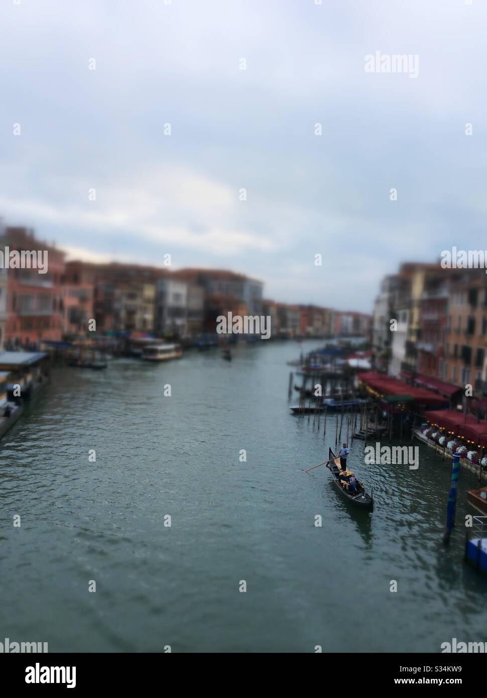 Tilt shift of a man sailing a gondola through the Rialto bridge in Venice, Italy Stock Photo