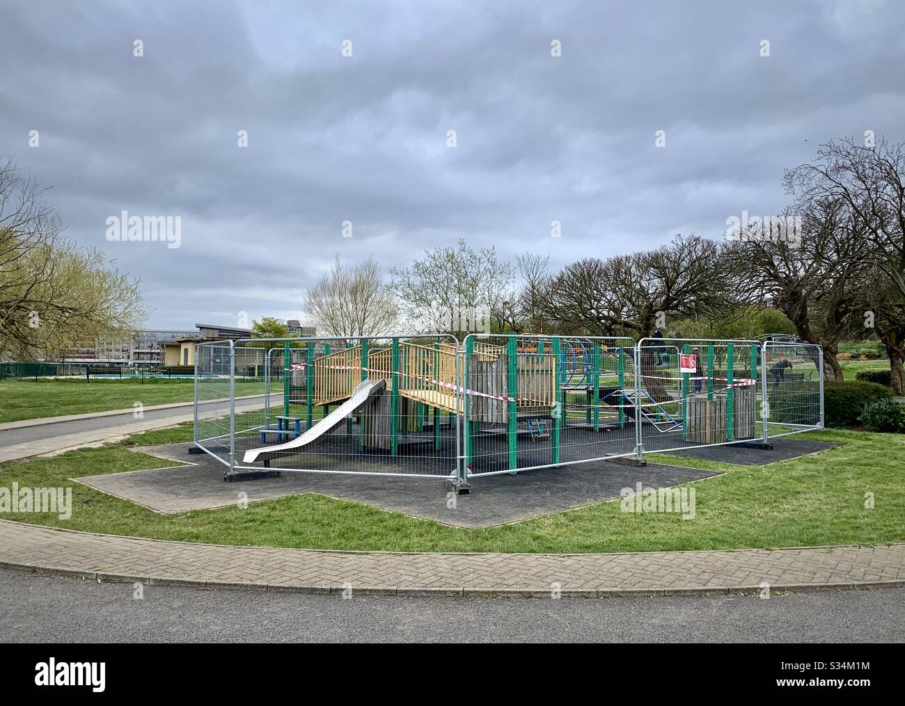 Metal fencing around children’s play equipment in a London park Stock Photo