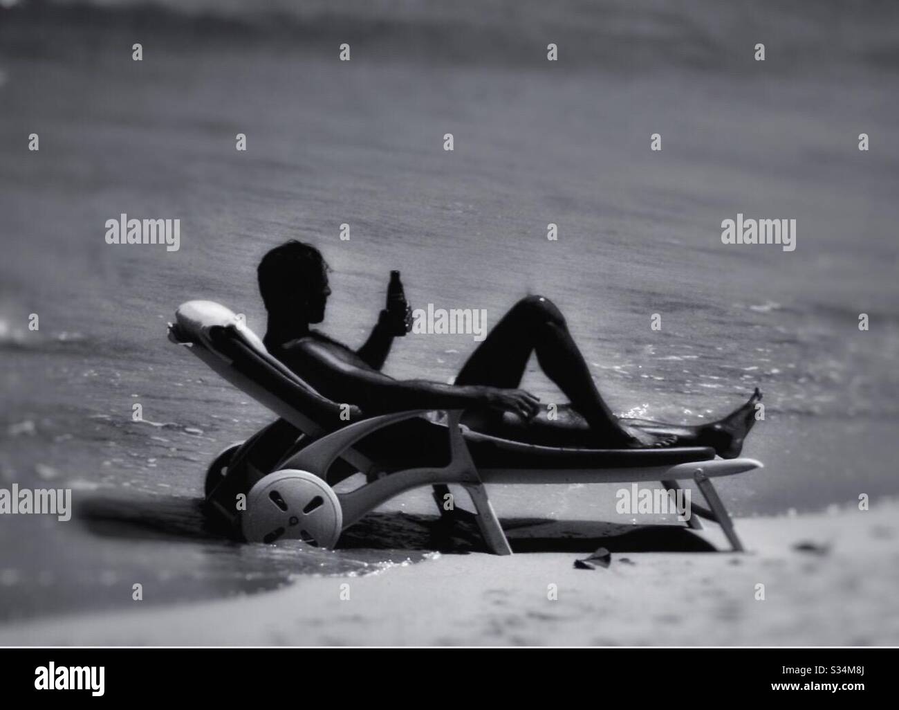 A man enjoying a drink on a tropical beach. - Smartphone Captured Stock Image