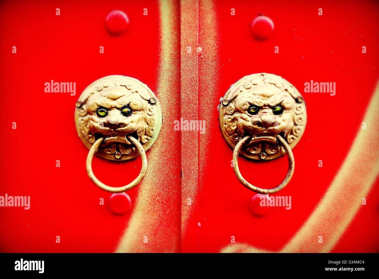 Gold Chinese Lion Heads with Rings on Red Door Stock Photo