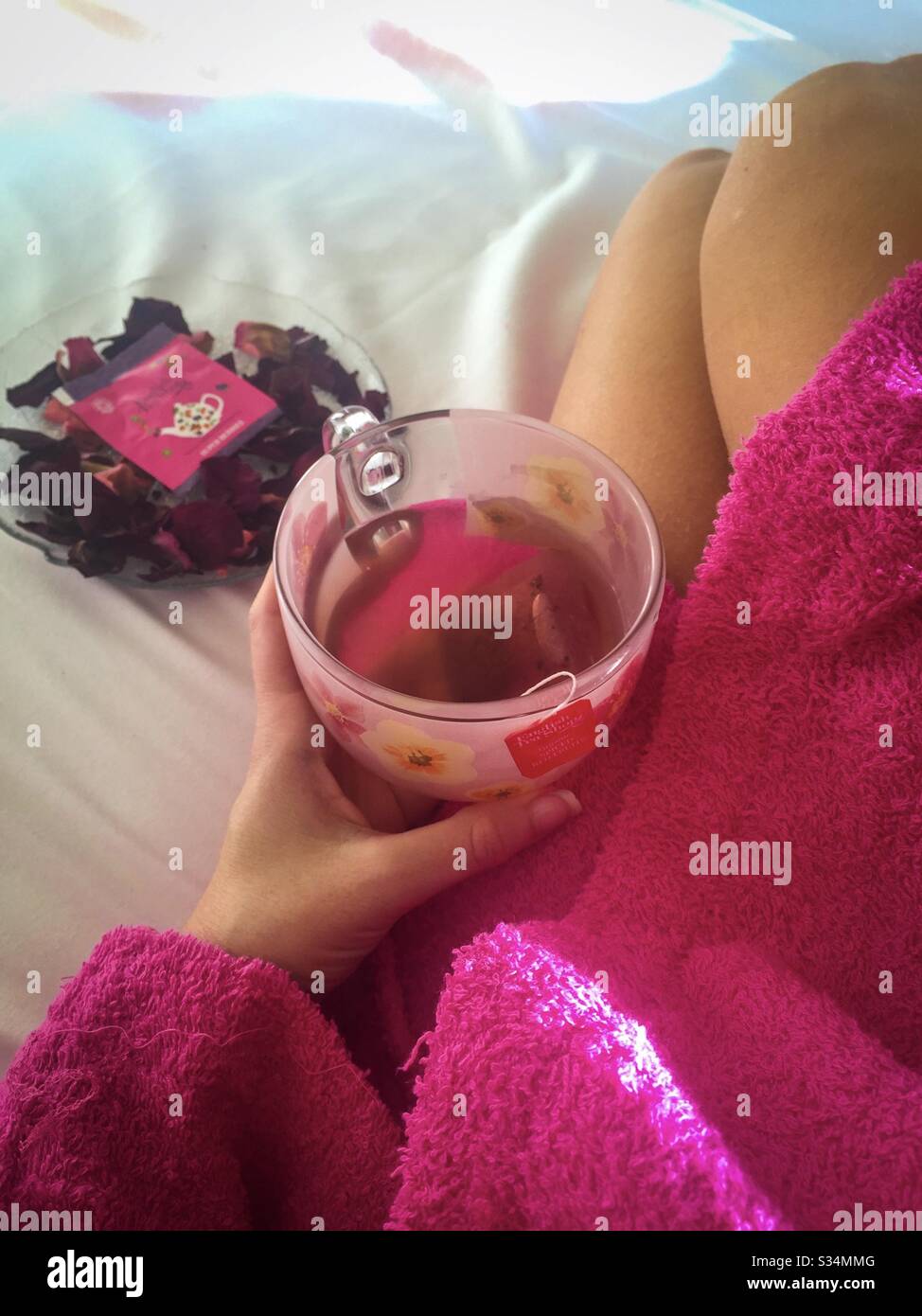 Woman in bed holding cup of tea in the morning light - Smartphone Captured Stock Image
