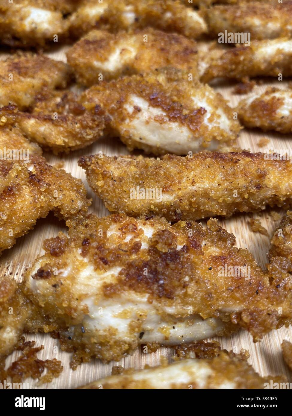 Closeup of homemade chicken nuggets/goujons in bamboo chopping board