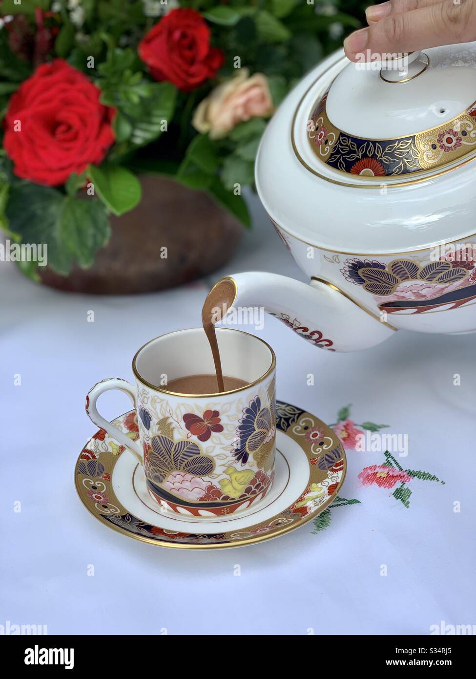 When morning greets you with pure hot chocolate served on fine bone China, a table with dainty linen and roses smiling at you.  What a glorious morning! Stock Photo