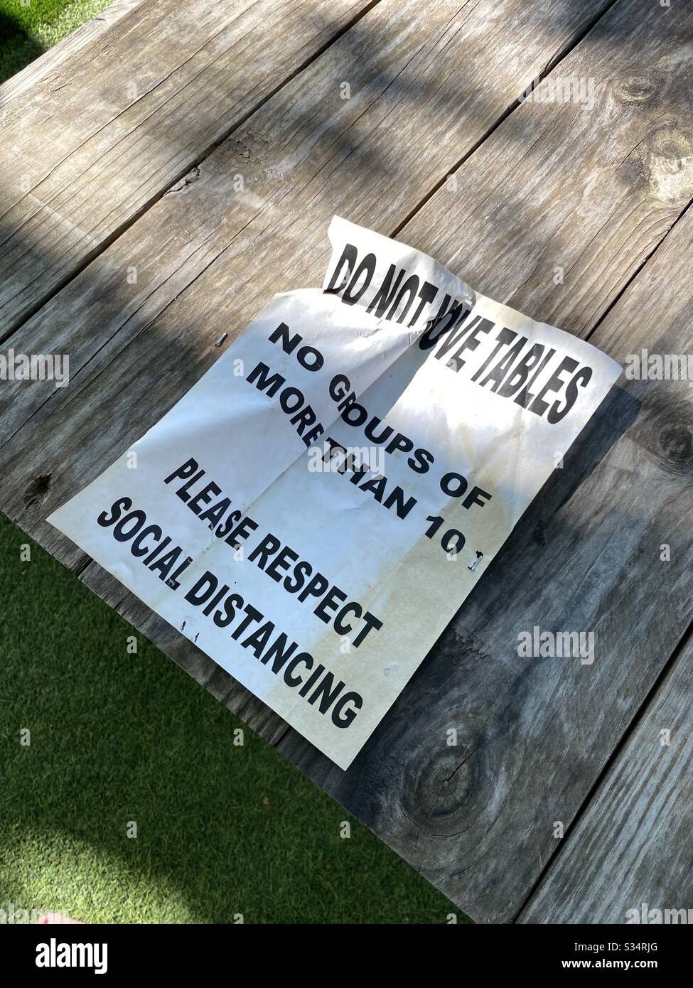 Crumpled paper with warning about social distancing due to coronavirus on an outdoor picnic bench April 1, 2020 - Smartphone Captured Stock Image