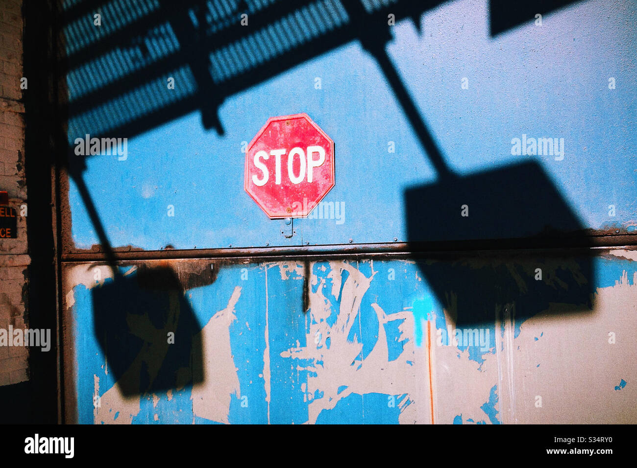 Stop Sign on Blue Garage Door with Peeling Paint Stock Photo