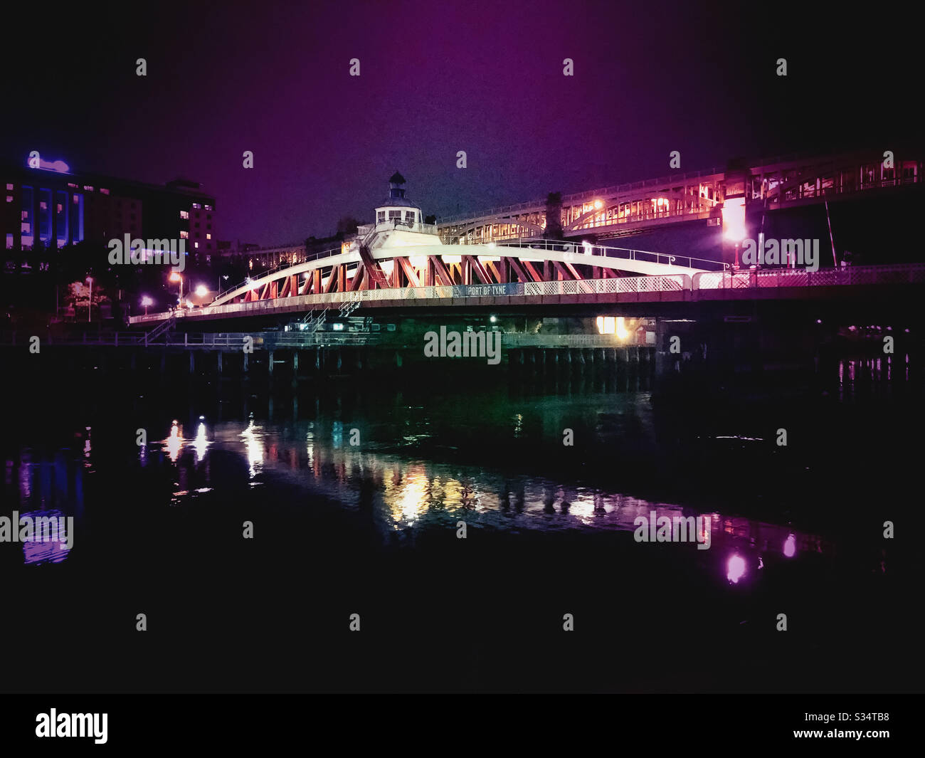 Architecture of Newcastle Quayside lit up by night. Newcastle upon Tyne, North East England. The Swing Bridge reflecting in the River Tyne. Illuminated with colorful lights - Smartphone Captured Stock Image