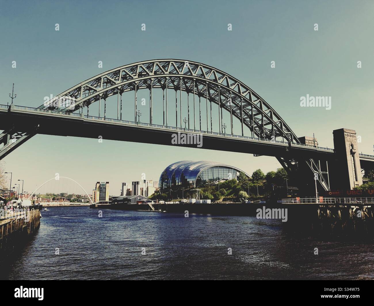 Architecture of Newcastle Quayside under a blue summer sky. Newcastle upon Tyne, North East England. The Tyne Bridge, Sage Gateshead and Millennium Bridge by the River Tyne. - Smartphone Captured Stock Image