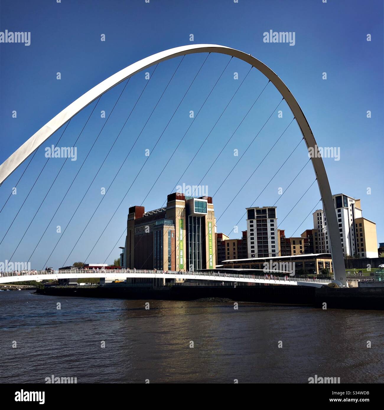 Architecture of Newcastle Quayside under a blue summer sky. Newcastle upon Tyne, North East England. The modern arched Millennium Bridge and Baltic Museum - Smartphone Captured Stock Image