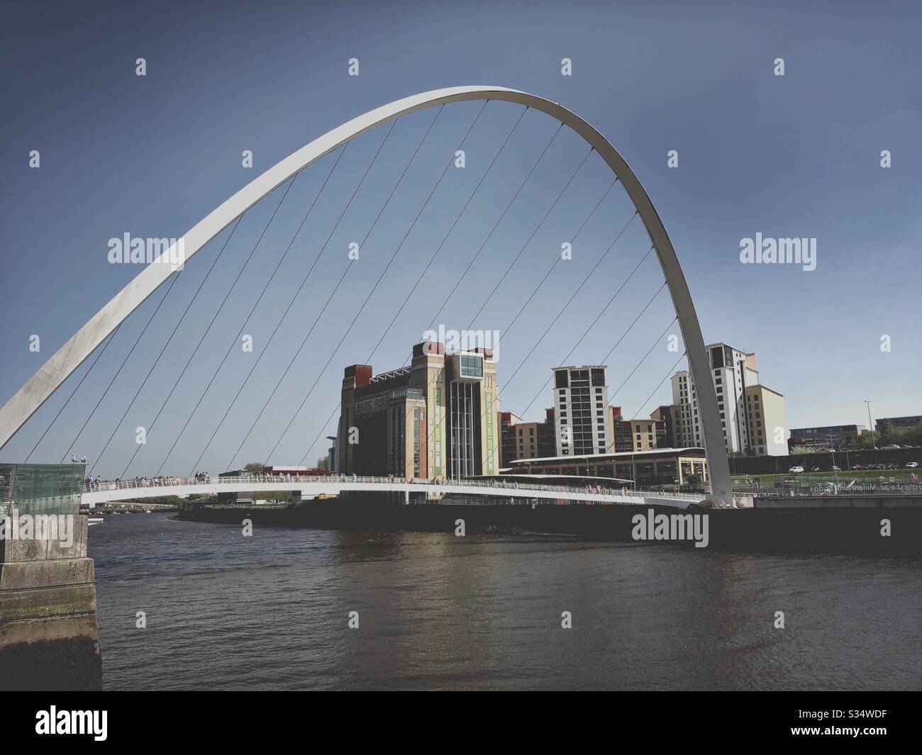 Architecture of Newcastle Quayside under a blue summer sky. Newcastle upon Tyne, North East England. The modern arched Millennium Bridge and Baltic Museum - Smartphone Captured Stock Image
