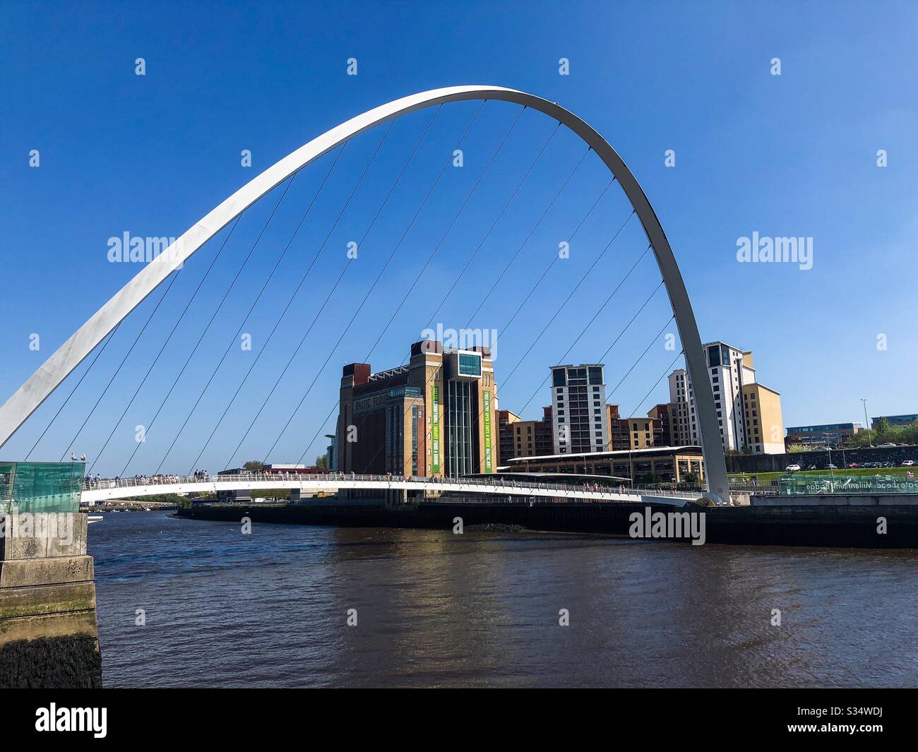 Architecture of Newcastle Quayside under a blue summer sky. Newcastle upon Tyne, North East England. The modern arched Millennium Bridge and Baltic Museum - Smartphone Captured Stock Image