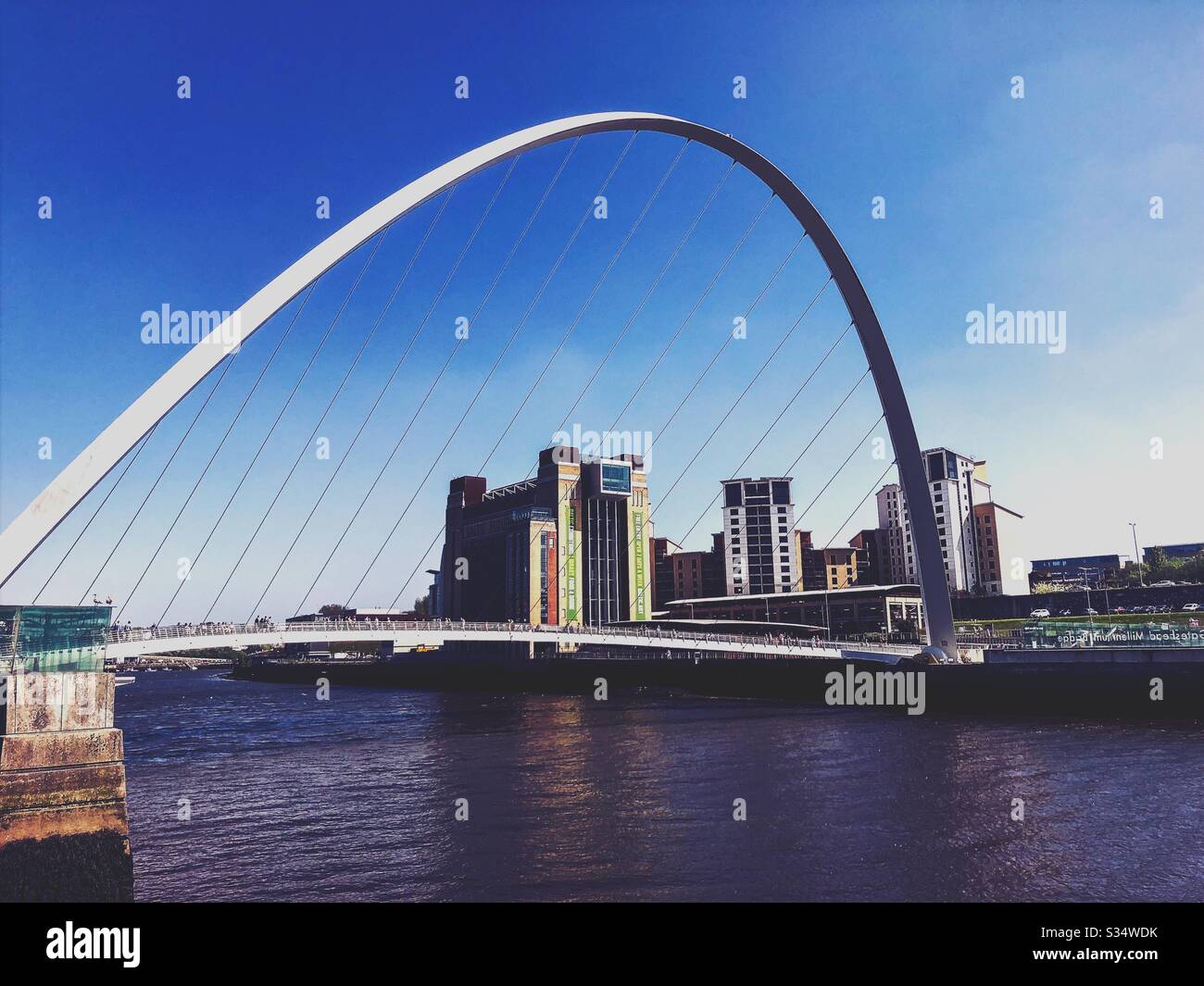 Architecture of Newcastle Quayside under a blue summer sky. Newcastle upon Tyne, North East England. The modern arched Millennium Bridge and Baltic Museum - Smartphone Captured Stock Image