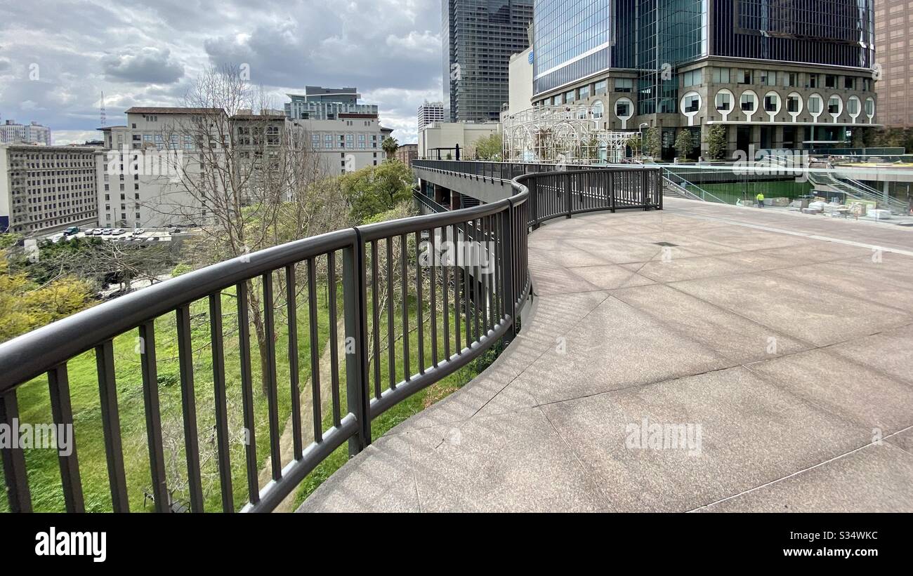 LOS ANGELES, CA, MAR 2020: curving railings next to empty outdoor space at California Plaza in Downtown. Construction worker can be seen on lower level - Smartphone Captured Stock Image