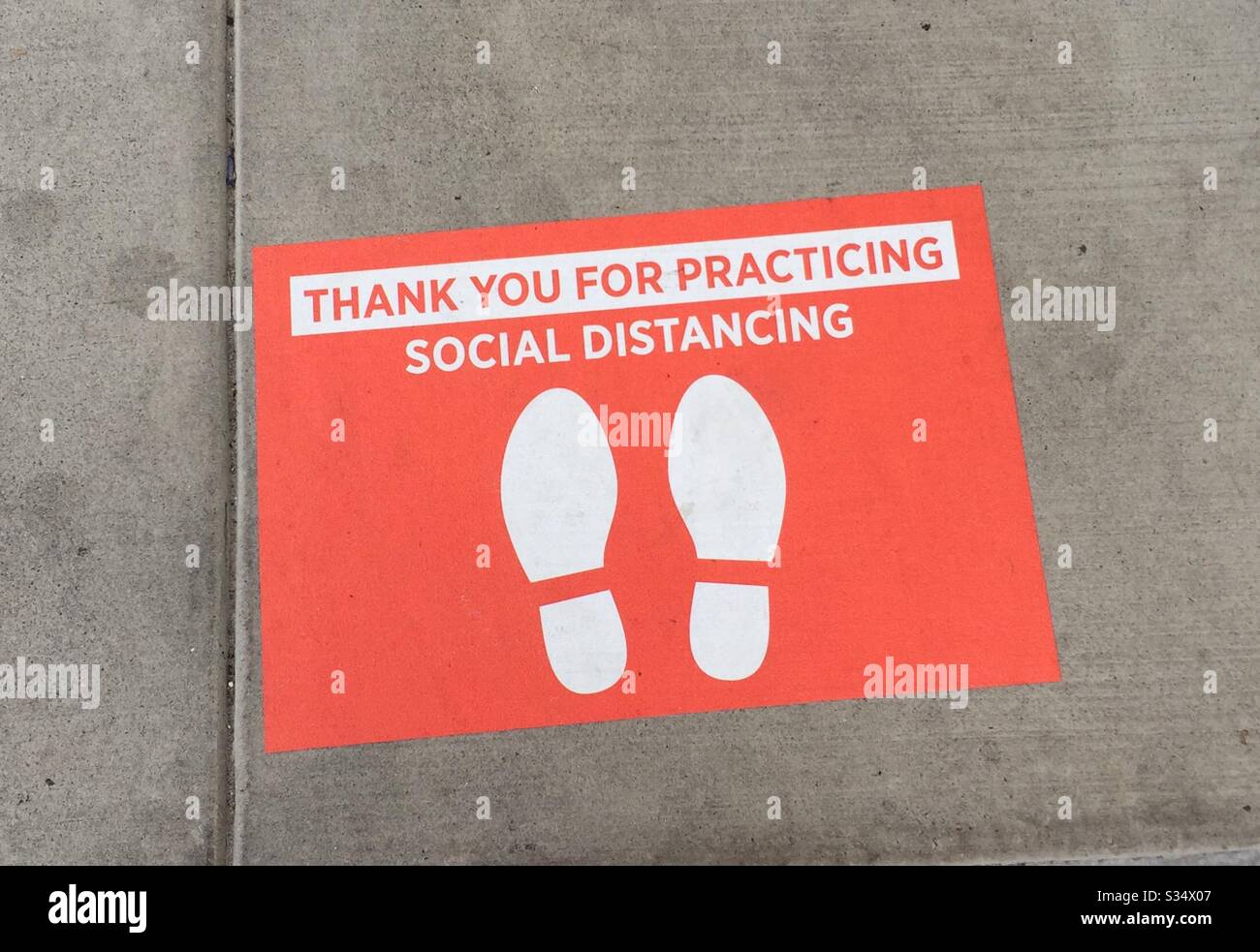 Floor sticker in front of grocery store, Houston, TX as a guideline for physical and social distancing - Smartphone Captured Stock Image
