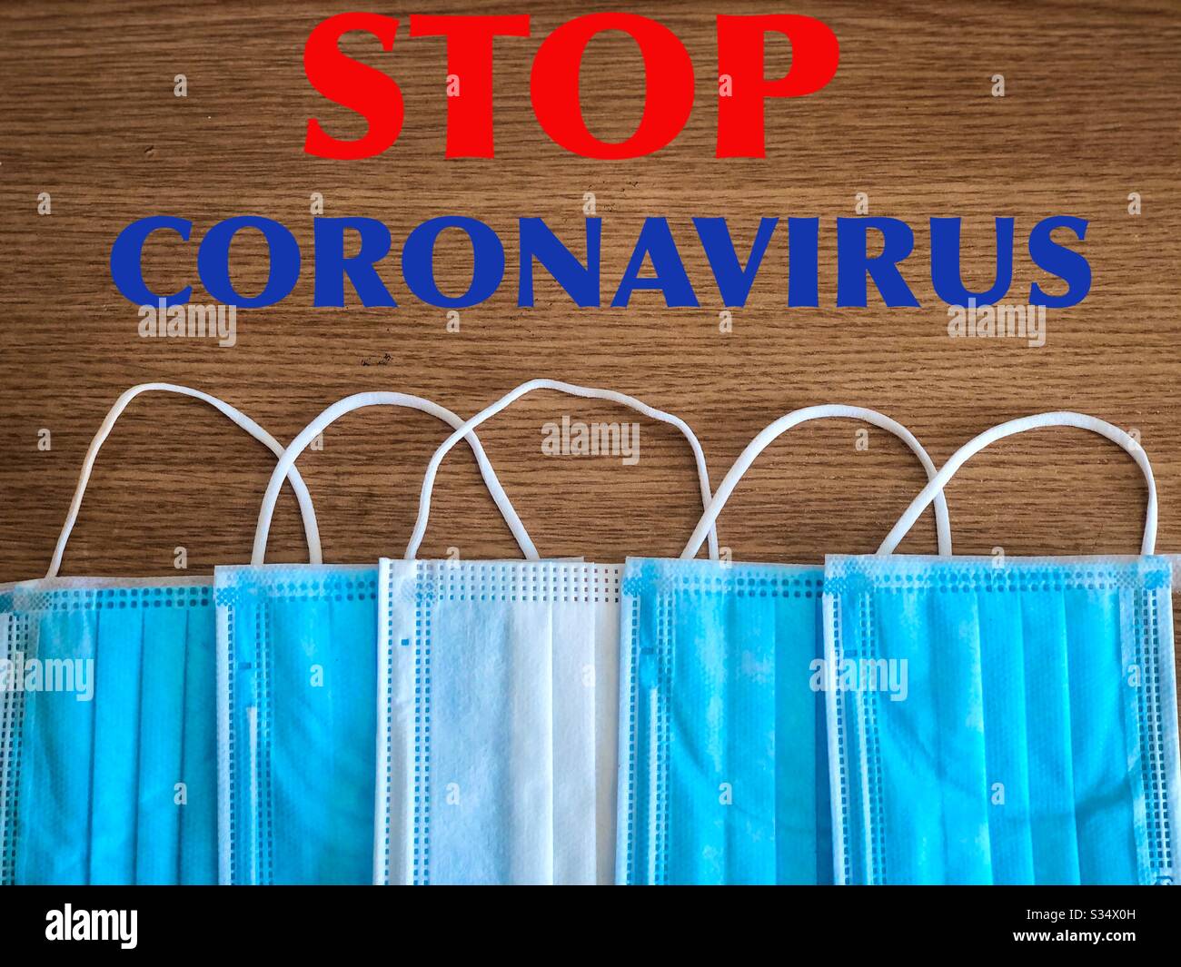 Multiple surgical masks on wooden table with the message to stop covid-19 - Smartphone Captured Stock Image