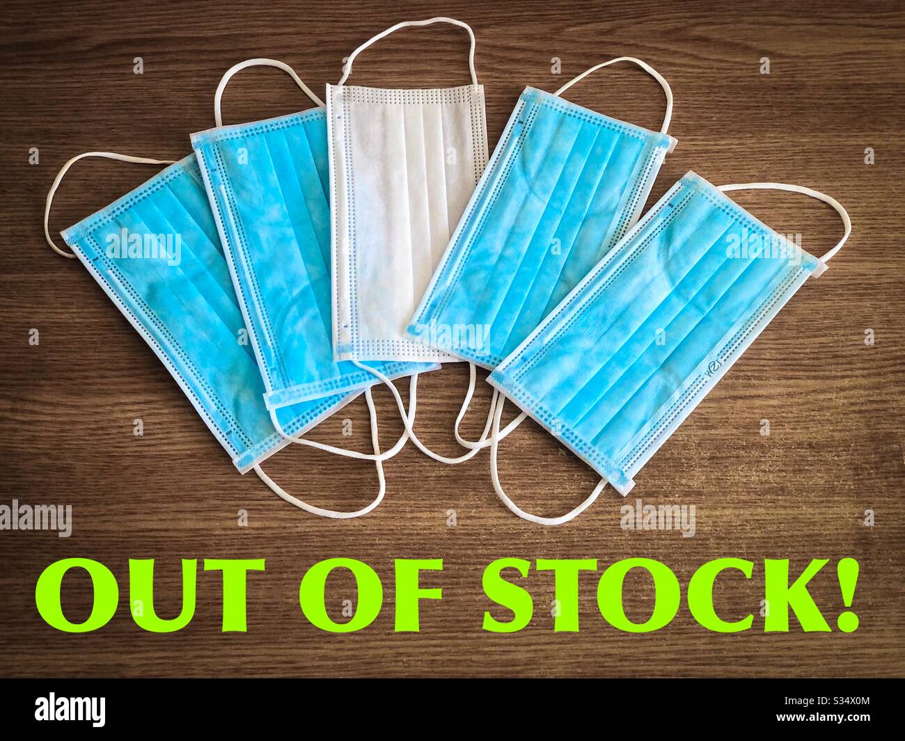 Multiple surgical masks on wooden table with the message “out of stock” - Smartphone Captured Stock Image