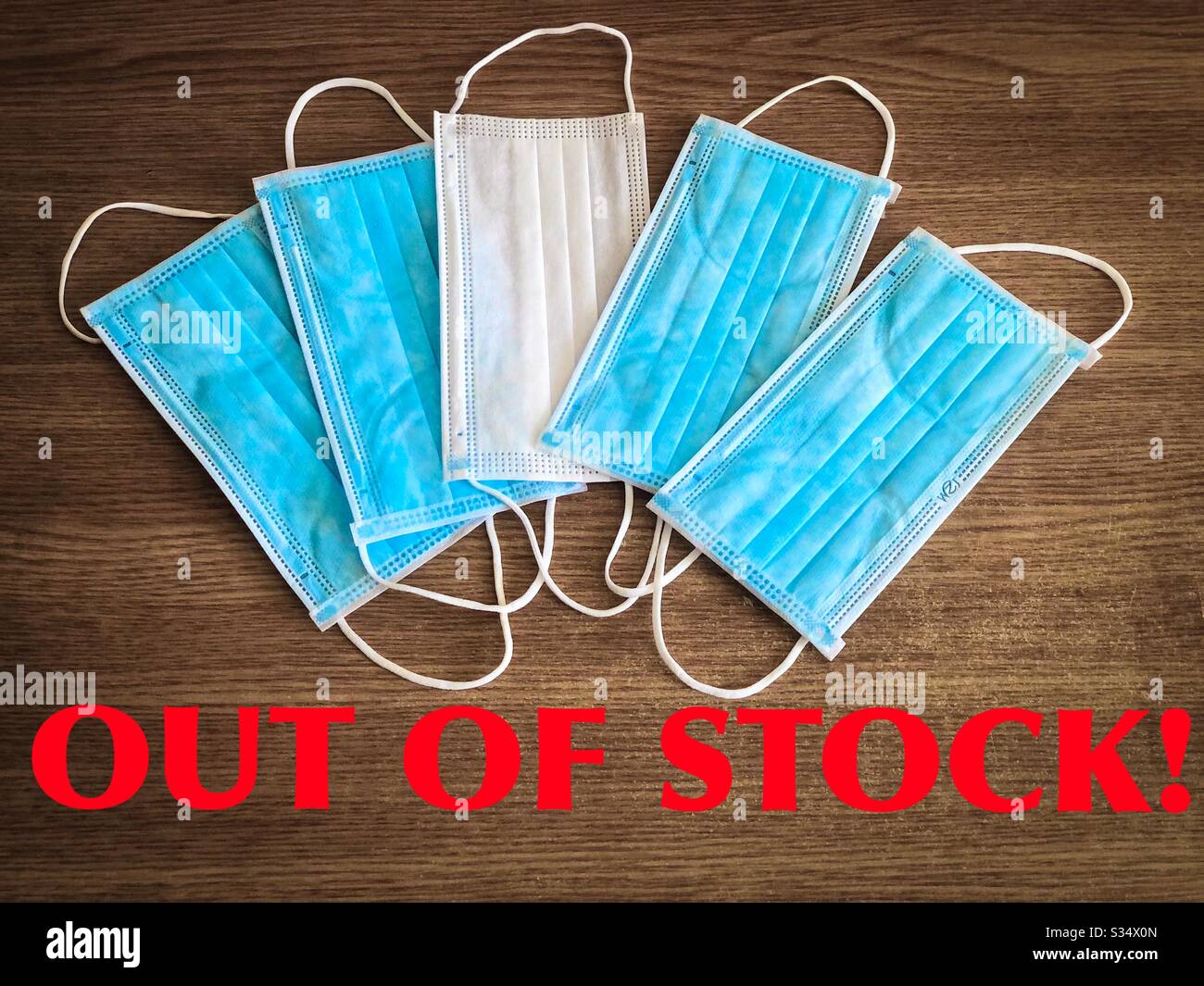 Multiple surgical masks on wooden table with the message “out of stock” - Smartphone Captured Stock Image