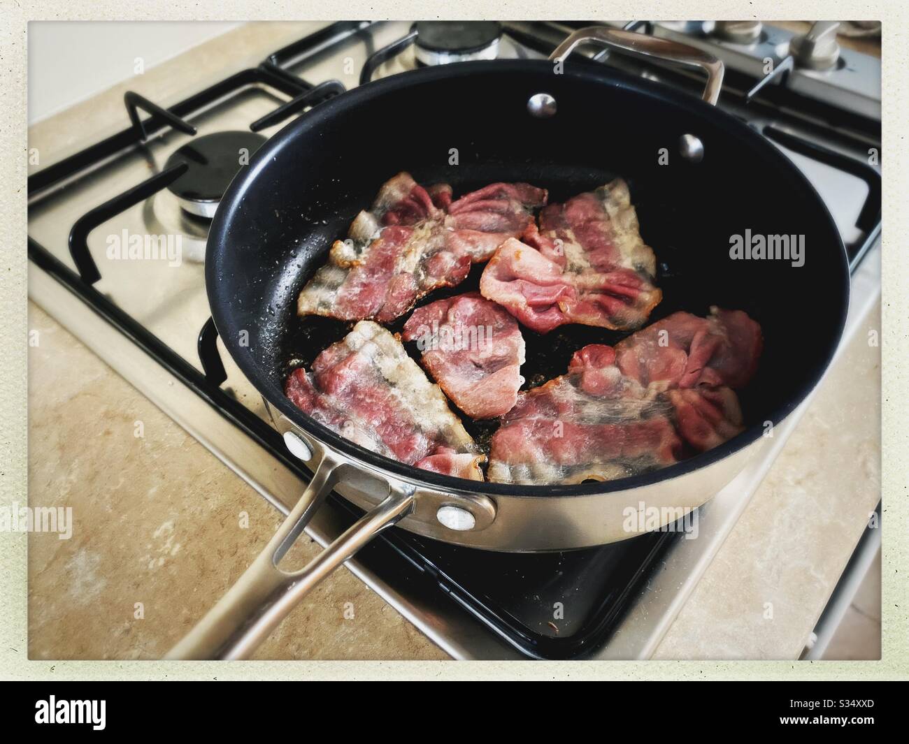 https://c8.alamy.com/comp/S34XXD/a-close-up-view-of-bacon-sizzling-in-the-frying-pan-on-a-stovetop-cooking-bacon-slices-for-breakfast-fry-up-S34XXD.jpg