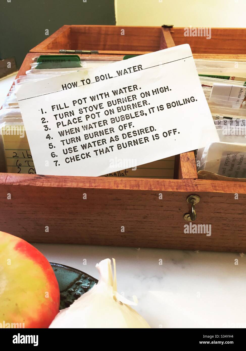 Recipe giving instructions on how to boil water in a handcrafted wooden recipe box on a residential kitchen counter, USA - Smartphone Captured Stock Image
