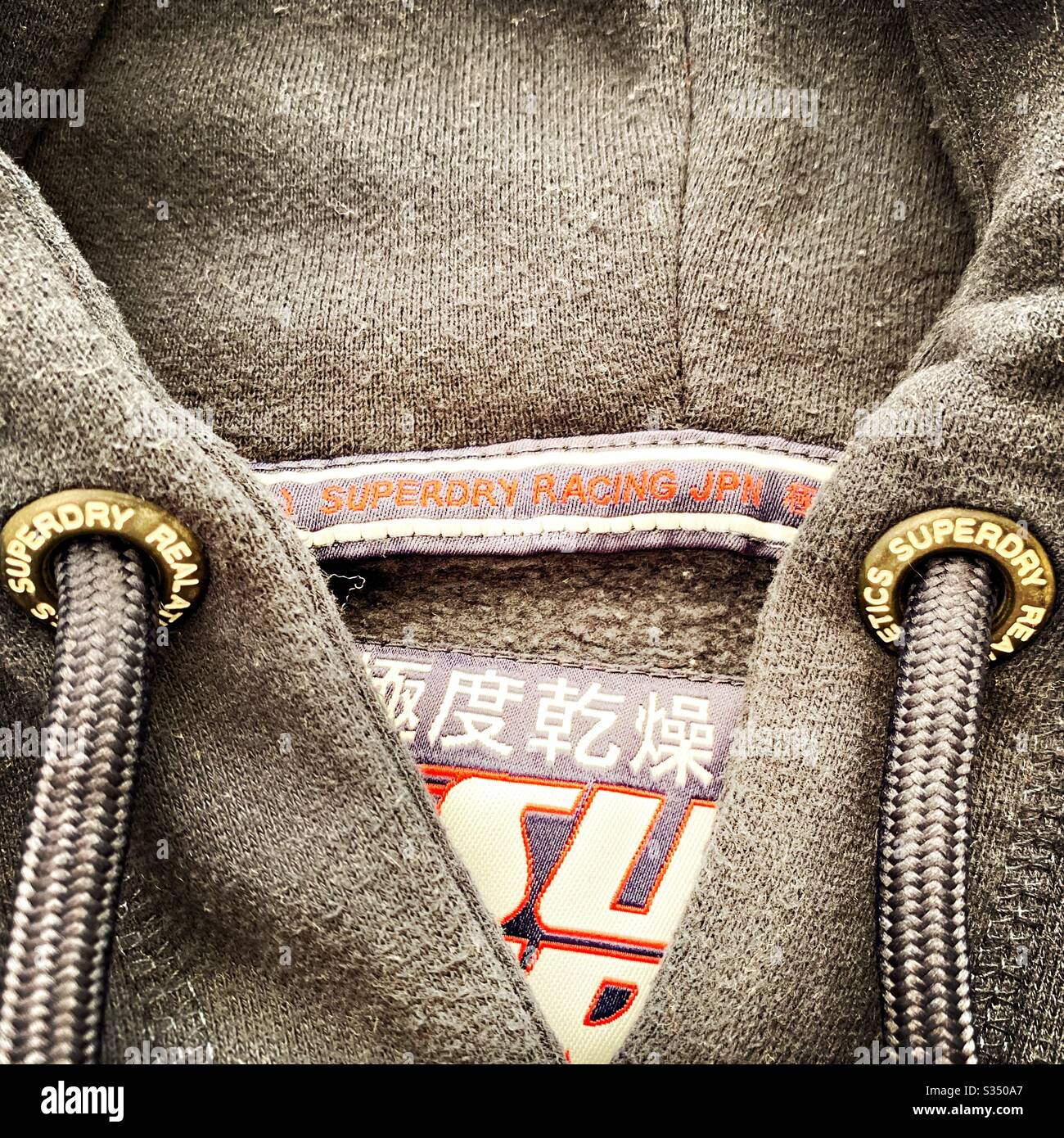Close up details of designer men’s clothes, menswear. Superdry hooded jumper, hoodie, hoody. Logo and branding - Smartphone Captured Stock Image