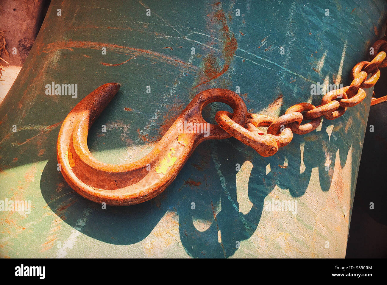 Rusty Hook and Chain on Scratched Green Metal Surface Stock Photo