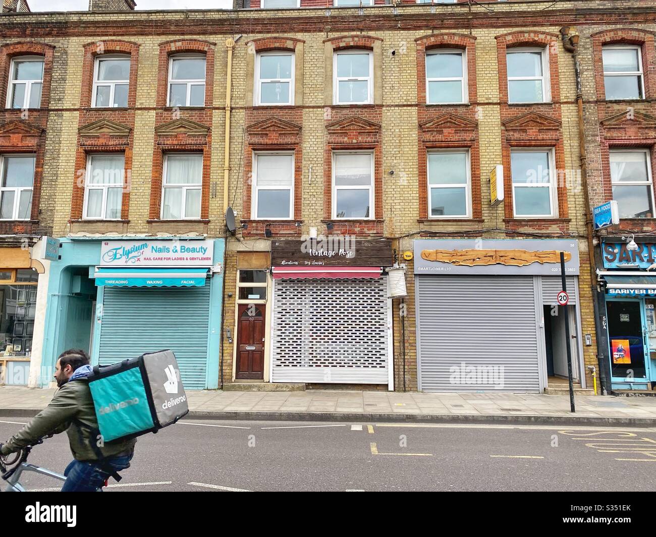 Empty street with shop shutters down during time of lockdown, Covid-19, Coronavirus, Green Lanes, Stoke Newington, north London - Smartphone Captured Stock Image