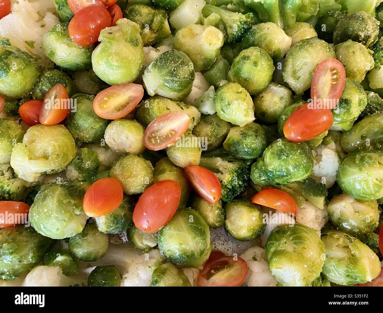 Beautifully oiled and salted green vegetable mixture with grape tomatoes ready for roasting