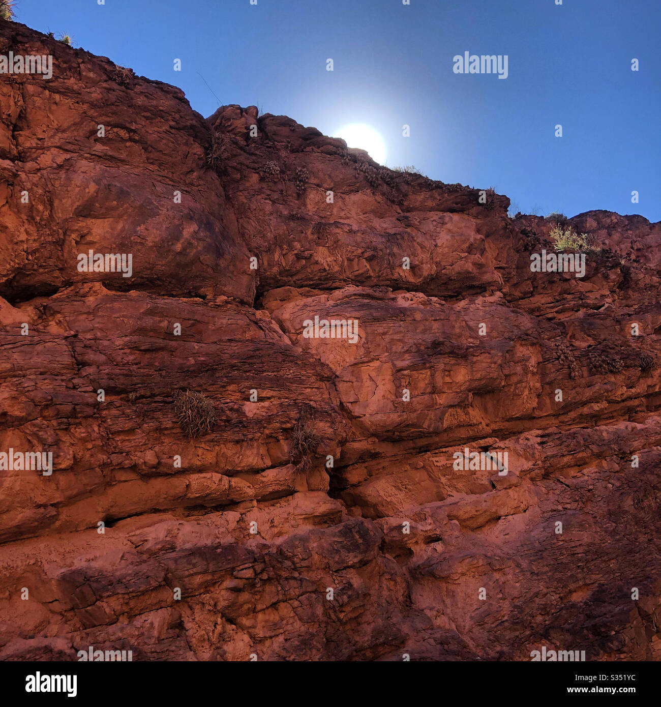 The sun peaks over the red rock formation in northern Argentina. - Smartphone Captured Stock Image