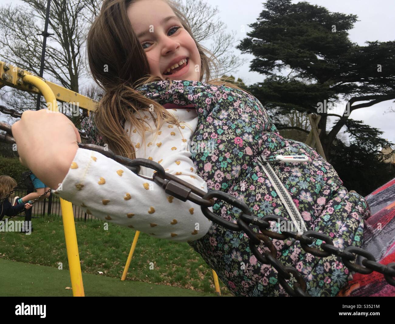 Young girl having fun on a swing in a park Stock Photo