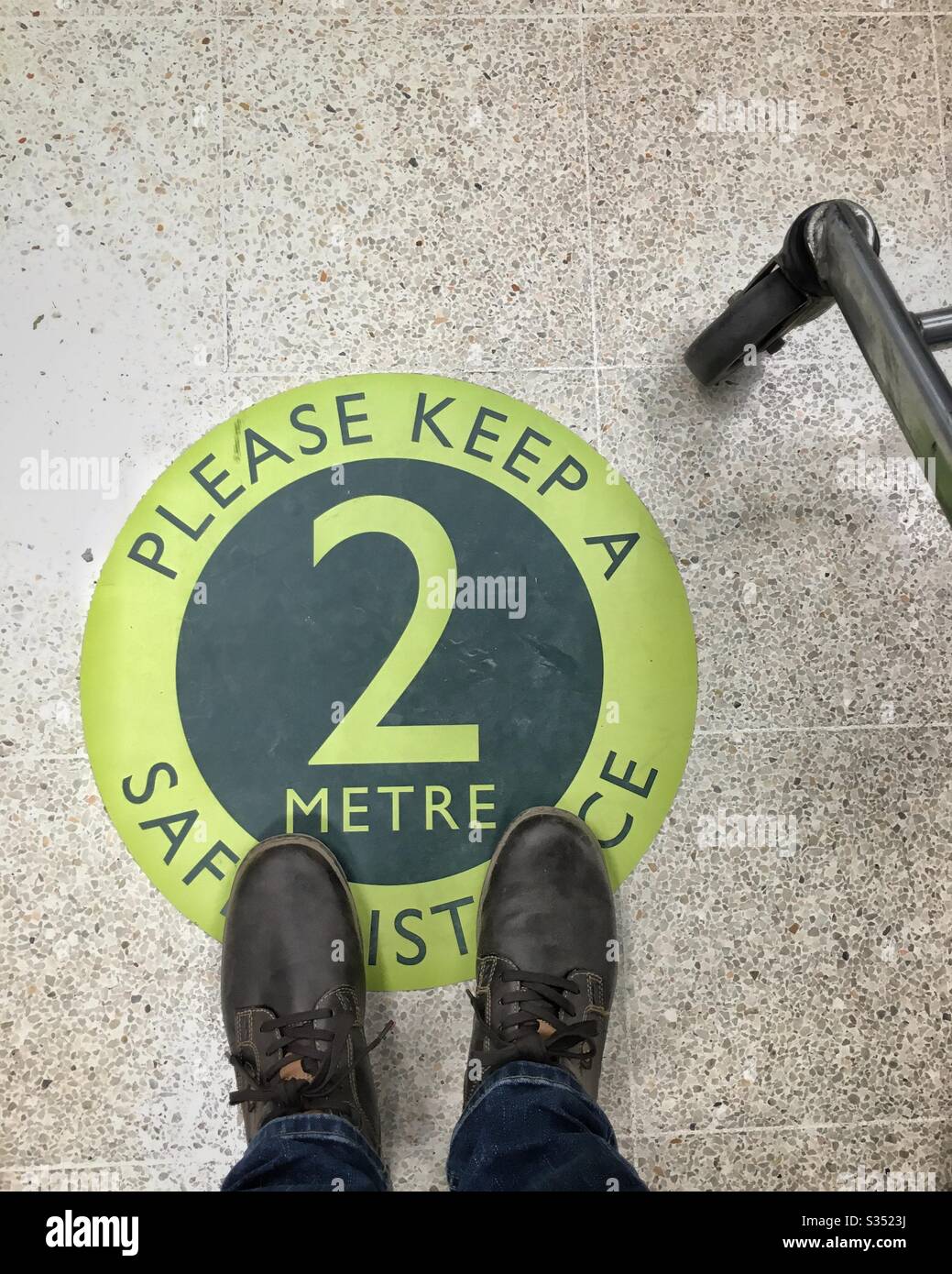 Social distancing; man's feet on a sign, Waitrose supermarket, UK - Smartphone Captured Stock Image