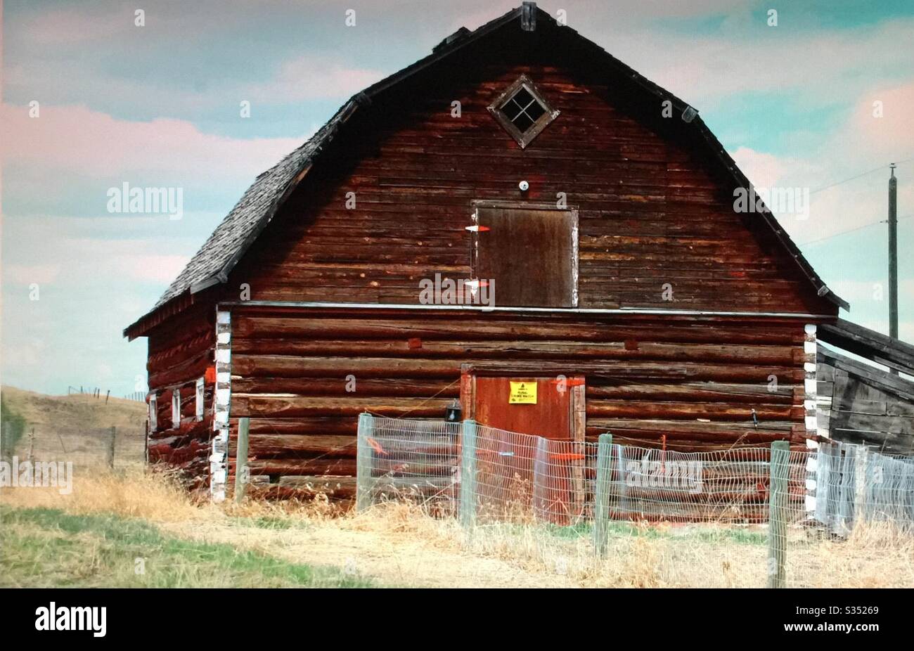 Old farmyard barns, agriculture, country life, wooden, structures,  Alberta, Canada, log barn, woods, foothills, trees,Pole fence, foothills, - Smartphone Captured Stock Image